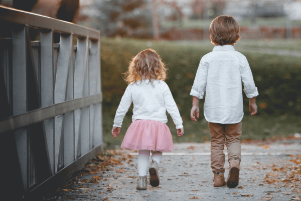 Een meisje en een jongen wandelen over een brug